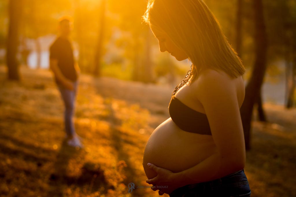 Mujer embarazada al atardecer acariciándose su barriga