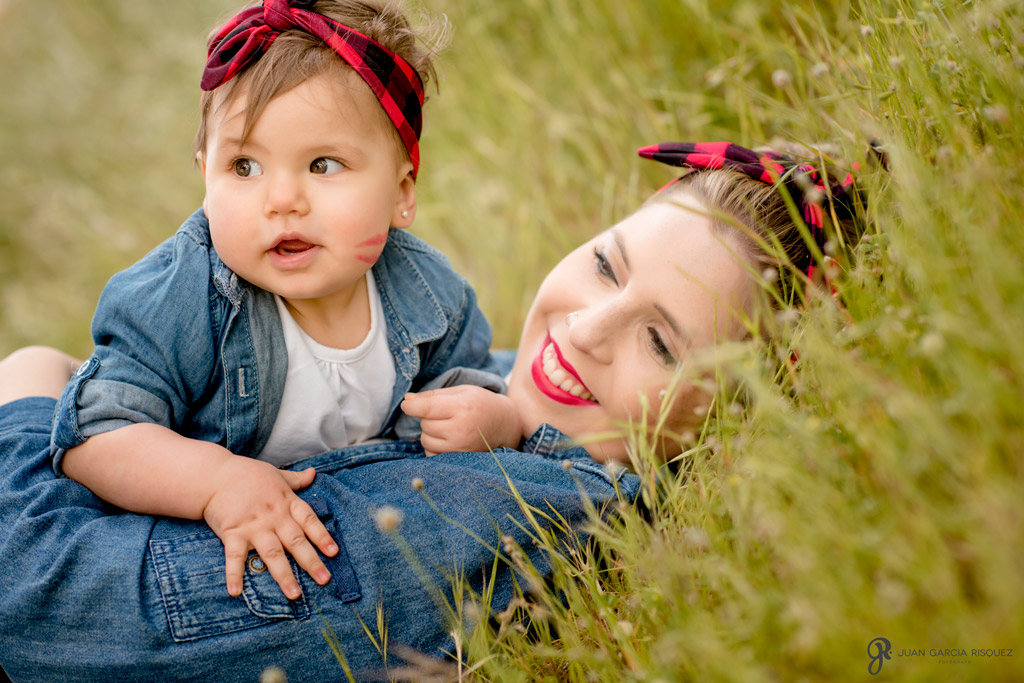 Foto de un bebé con su mamá tumbadas en un campo